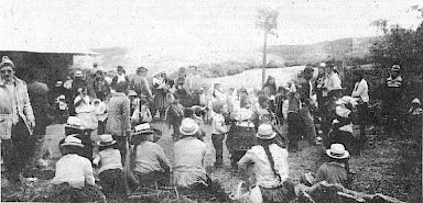 Nach dem Gottesdienst in den Anden sitzen die Indios noch zu einem Schwätz zusammen. Vor der Hütte links war ein Gottesdienst zelebriert worden; Franz Holzmann war dabei, zusammen mit einem weiteren Europäer (links im Bild erkennbar; ein Österreicher, der die Steyler Niederlassung in Cuenca über Weihnachten besuchte). Attraktion des kleinen Festes war ein Kletterbaum für die Indiokinder (im Bild rechts der Mitte erkennbar); seine Besonderheit: als Preis baumelten hier einige Cola-Flaschen.